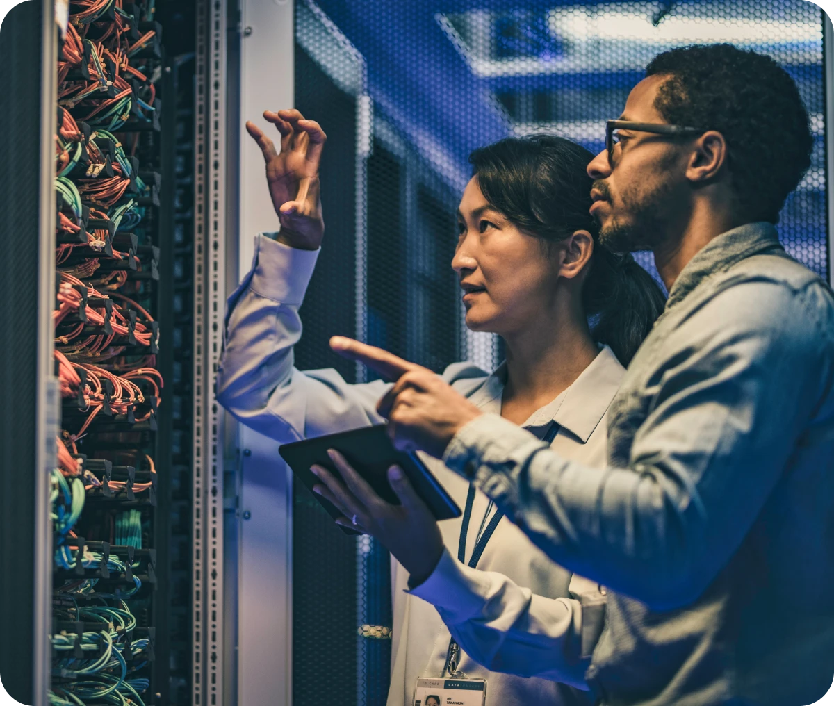 Technicians examining server cables in data center.